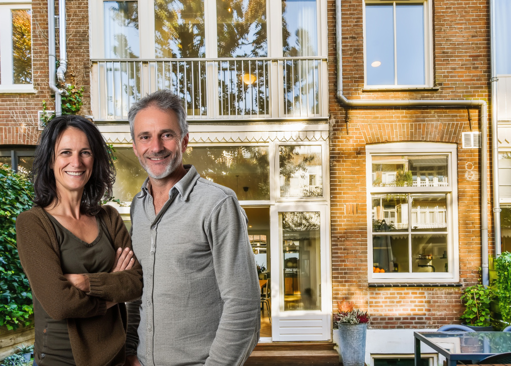 echtpaar staat voor de achterkant van hun rijtjeshuis