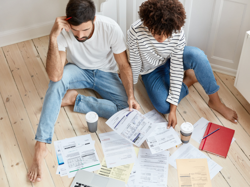 Jong stel zit op de grond met allerlei paperassen om zich heen